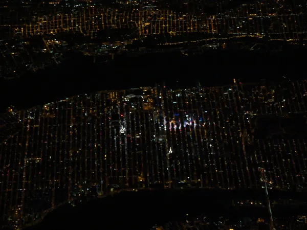 Manhattan with Times Square in the brightest colored lights and the perfectly visible dead straight 'Streets' that divide the city horizontally. Above (the dark part) the Hudson River.